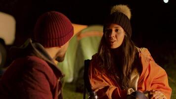 Close friends around camp fire in a cold night in mountains. Retro camper. Camping tent video