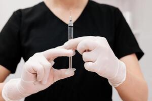 Hand holding a syringe, the syringe is filled with clear liquid. Injection procedure. Lip augmentation, close-up. Advertising concept for facial care photo