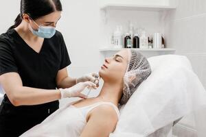 Injection procedure. The cosmetologist slowly and carefully injects filler into the chin. Advertising concept for facial care, youth and beauty. photo