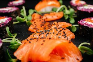 rebanado Fresco salmón plato en negro antecedentes. salmón sashimi con negro sésamo, con Copiar espacio. alto calidad foto