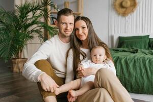 Portrait of a beautiful young family with a baby at home photo