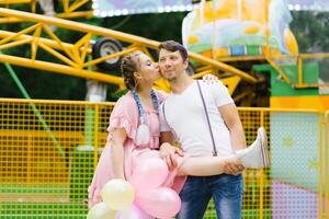 Young happy funny couple in love walks and has fun in an amusement park photo
