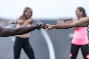 Crop diverse friends bumping fists during training photo