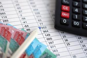 Business calculations with indonesian rupiah money bills and calculator with pen on office table photo