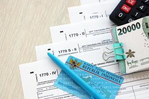 Annual Individual Income Tax Return forms with pen and indonesian rupiah bills photo