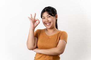 The cheerful young Asian woman smiling and showing the OK hand sign standing on white background. photo