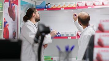 équipe de pharmaciens assurer des produits Stock dans une pharmacie, compte tout médicaments et diététique suppléments sur étagères. pharmacie Personnel membres travail ensemble à faire inventaire. video