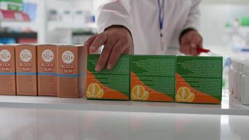 POV of druggist taking nutritional vitamins boxes from shelves, replacing them with other medication. Employee rearranging pharmaceutical products in healthcare facility. Tripod shot. video