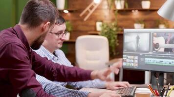 Bearded young videographer in the office talking with his manager. Video editor.