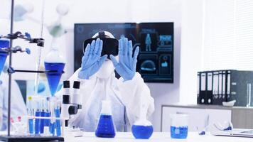 jovem fêmea cientista dentro química laboratório com virtual realidade fone de ouvido ampliando fora. molécula do azul solução fumar. cientista dentro a fundo colocando uma diagnóstico. video