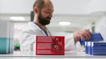 pov de farmacéutico tomando medicamentos desde farmacia estantes, trabajando en reorganizando remedios y suplementos en un farmacia. masculino trabajador vaciando bastidores de vitaminas y tratos. trípode disparo. video