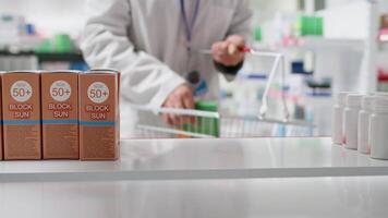 POV of pharmacist putting natural vitamins boxes on shelves, arranging healthcare products for customers. Medical specialist placing dietary supplements on display at drugstore. Tripod shot. video