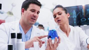 team van vrouw en mannetje onderzoeker in de laboratorium analyseren een blauw roken vloeistof video