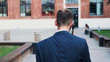 Man in business suit walking in the city and talking on the phone, back view slow motion tracking shot video