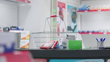 Basket with variety of pills and box shows greenscreen template at drugstore checkout counter. Empty pharmacy store selling pharmaceutical products and a pack with blank chromakey mockup. video