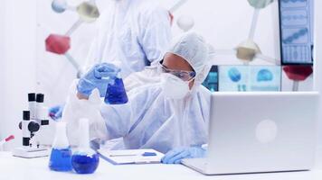 ricerca scienziato nel chimico industria Lavorando con fumo blu fluido indossare tuta attrezzatura. scienziato collega porzione con ricerca. video