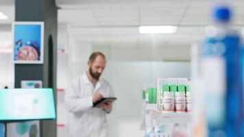 médico trabajador contando medicamentos cajas metido en estantes, trabajando en farmacia inventario a garantizar lleno valores para clientela. farmacéutico haciendo logístico actividad con paquetes de pastillas video