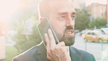 retrato do bonito homem de negocios falando em a telefone enquanto lente chamas estão batendo a tela. lento movimento fechar acima video