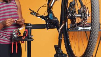 africano americano mecánico utilizando diferente herramientas a reparar dañado bicicleta manillar apretones, estudio antecedentes. empleado utilizando especializado engranaje a reparar cambiadores y freno palancas en bicicleta, cámara un video