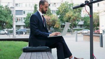 Mens in bedrijf pak typen Aan de laptop buitenshuis van zijn kantoor in de stad. werken Aan de Gaan concept video