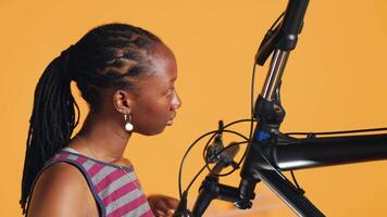 BIPOC technician uses screwdriver to unmount bicycle handlebars, testing components quality in studio background atelier shop. Specialist mechanic unscrewing bike parts in order to mend them, camera A video