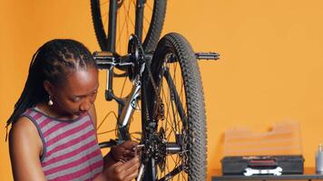 Specialist using screwdriver and hex socket wrench to secure wheel on bicycle in studio background repair shop. Technician screwing bolts on bike parts, fixing rear derailleur, camera A video