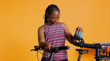 Atelier shop employee setting up bike repair stand before starting work on busted wheels, studio background. Professional securing bicycle on workstand before examining for damages, camera B video