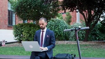 zakenman werken Aan de laptop buitenshuis, langzaam beweging zoom in filmmateriaal. bedrijf Aan de Gaan video