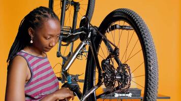 Specialist using screwdriver and hex socket wrench to secure wheel on bicycle in studio background repair shop. Technician screwing bolts on bike parts, fixing rear derailleur, camera B video