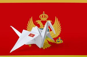 Montenegro flag depicted on paper origami crane wing. Handmade arts concept photo