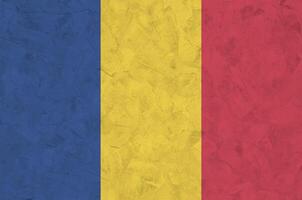 Romania flag depicted in bright paint colors on old relief plastering wall. Textured banner on rough background photo