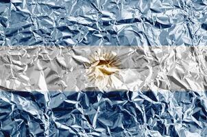 Argentina flag depicted in paint colors on shiny crumpled aluminium foil closeup. Textured banner on rough background photo