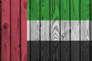 unido árabe emiratos bandera representado en brillante pintar colores en antiguo de madera pared. texturizado bandera en áspero antecedentes foto