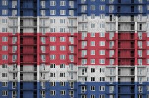 Costa Rica flag depicted in paint colors on multi-storey residental building under construction. Textured banner on brick wall background photo