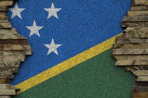 Solomon Islands flag depicted in paint colors on old stone wall closeup. Textured banner on rock wall background photo