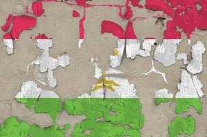 Tajikistan flag depicted in paint colors on old obsolete messy concrete wall closeup. Textured banner on rough background photo