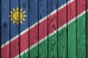Namibia flag depicted in bright paint colors on old wooden wall. Textured banner on rough background photo