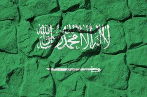 saudi arabia bandera representado en pintar colores en antiguo Roca pared de cerca. texturizado bandera en rock pared antecedentes foto