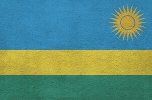 Rwanda flag depicted in bright paint colors on old relief plastering wall. Textured banner on rough background photo