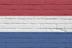 Netherlands flag depicted in paint colors on old brick wall. Textured banner on big brick wall masonry background photo