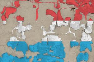 Luxembourg flag depicted in paint colors on old obsolete messy concrete wall closeup. Textured banner on rough background photo