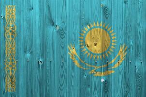 Kazajstán bandera representado en brillante pintar colores en antiguo de madera pared. texturizado bandera en áspero antecedentes foto