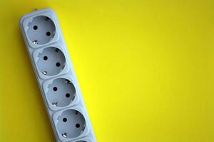 White electrical multi plug extender with european socket on bright yellow background photo