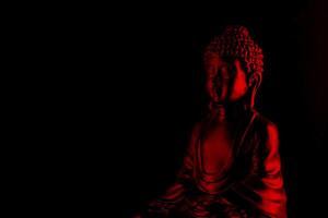 Buda purnima y vesak día concepto, rojo Buda estatua con bajo llave ligero en contra profundo negro antecedentes foto