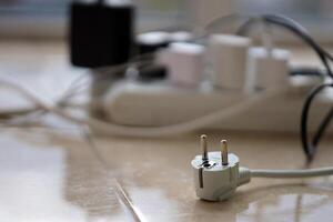 Overloaded power boards. Power strips with different electrical plugs on white floor photo