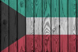 Kuwait bandera representado en brillante pintar colores en antiguo de madera pared. texturizado bandera en áspero antecedentes foto