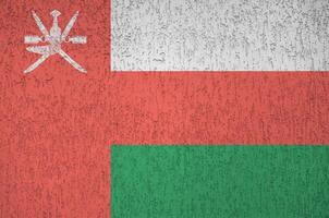 Oman flag depicted in bright paint colors on old relief plastering wall. Textured banner on rough background photo