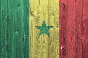 Senegal flag depicted in bright paint colors on old wooden wall. Textured banner on rough background photo