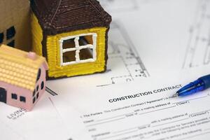 Residential construction agreement ready to sign with small toy houses and pen. Construction contract photo