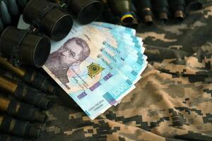 Ukrainian army machine gun belt shells and bunch of hryvnia bills on military uniform. Payments to soldiers of the Ukrainian army, salaries to the military photo